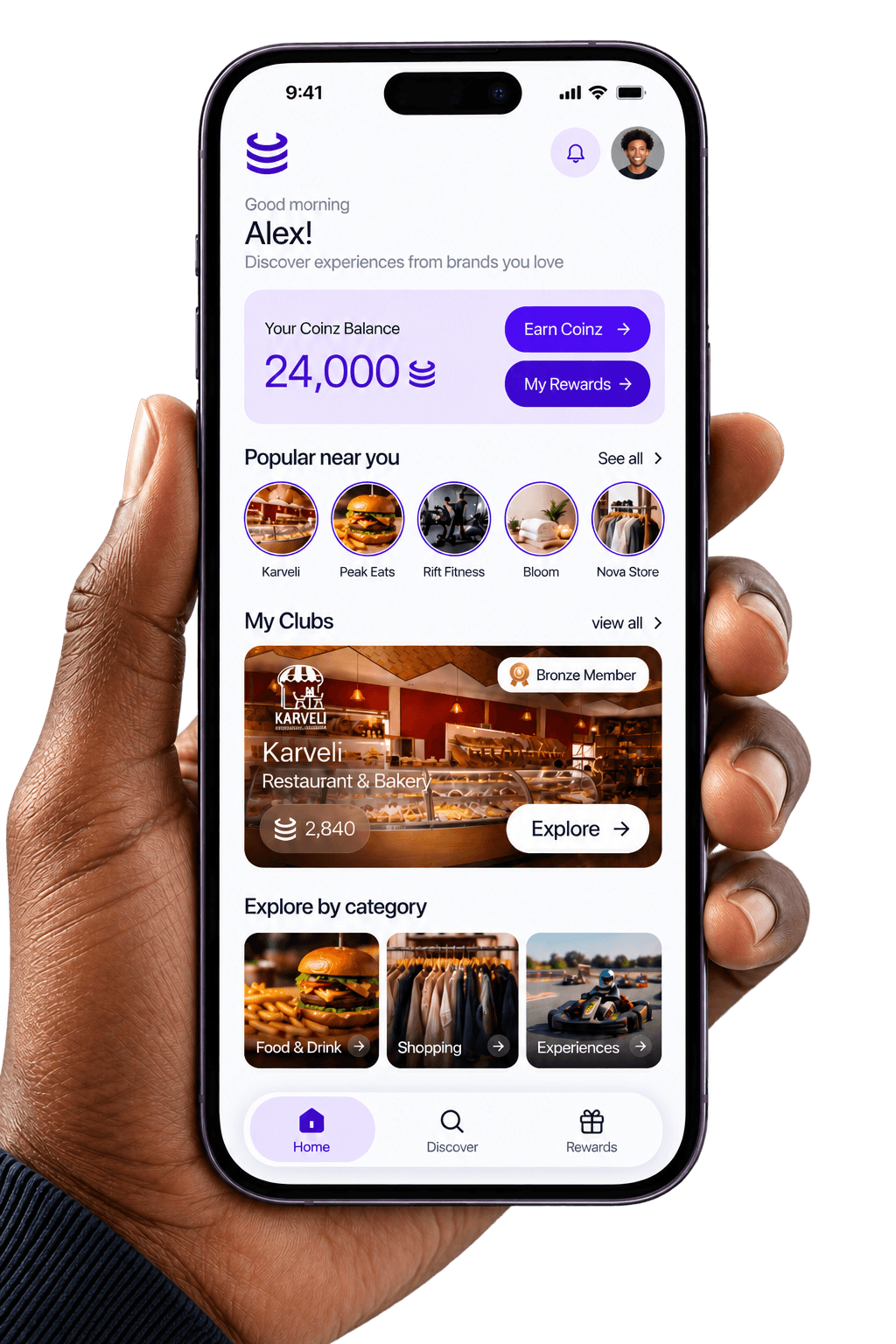A hand holding a phone showing the Coinz app: a balance of 24,000 Coinz, with places to earn nearby